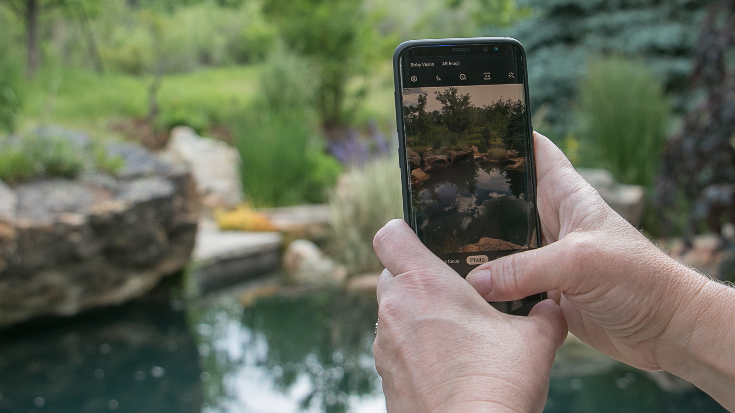 Woman taking a photo with smartphone in garden