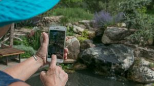 Janet photographs a waterfall in a garden with her smartphone